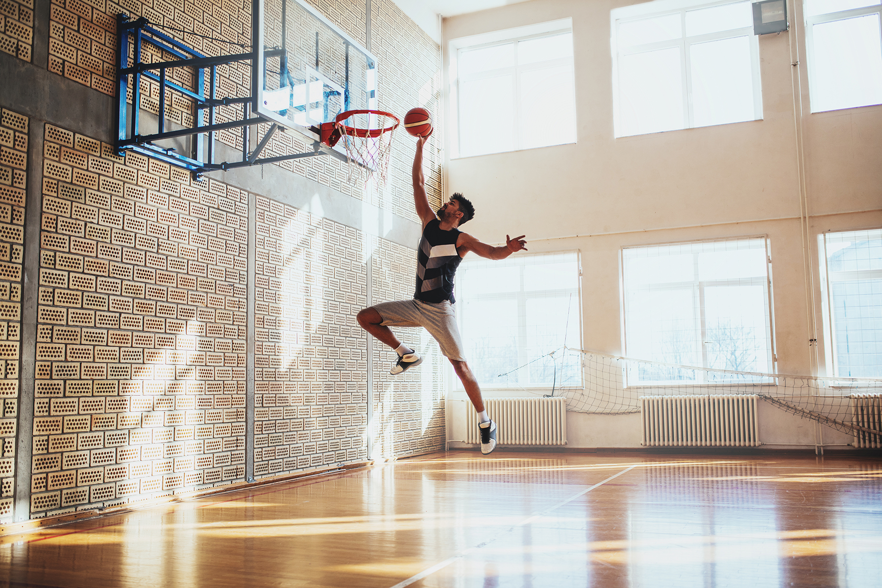 Man jumping up toward a hoop with a basketball
