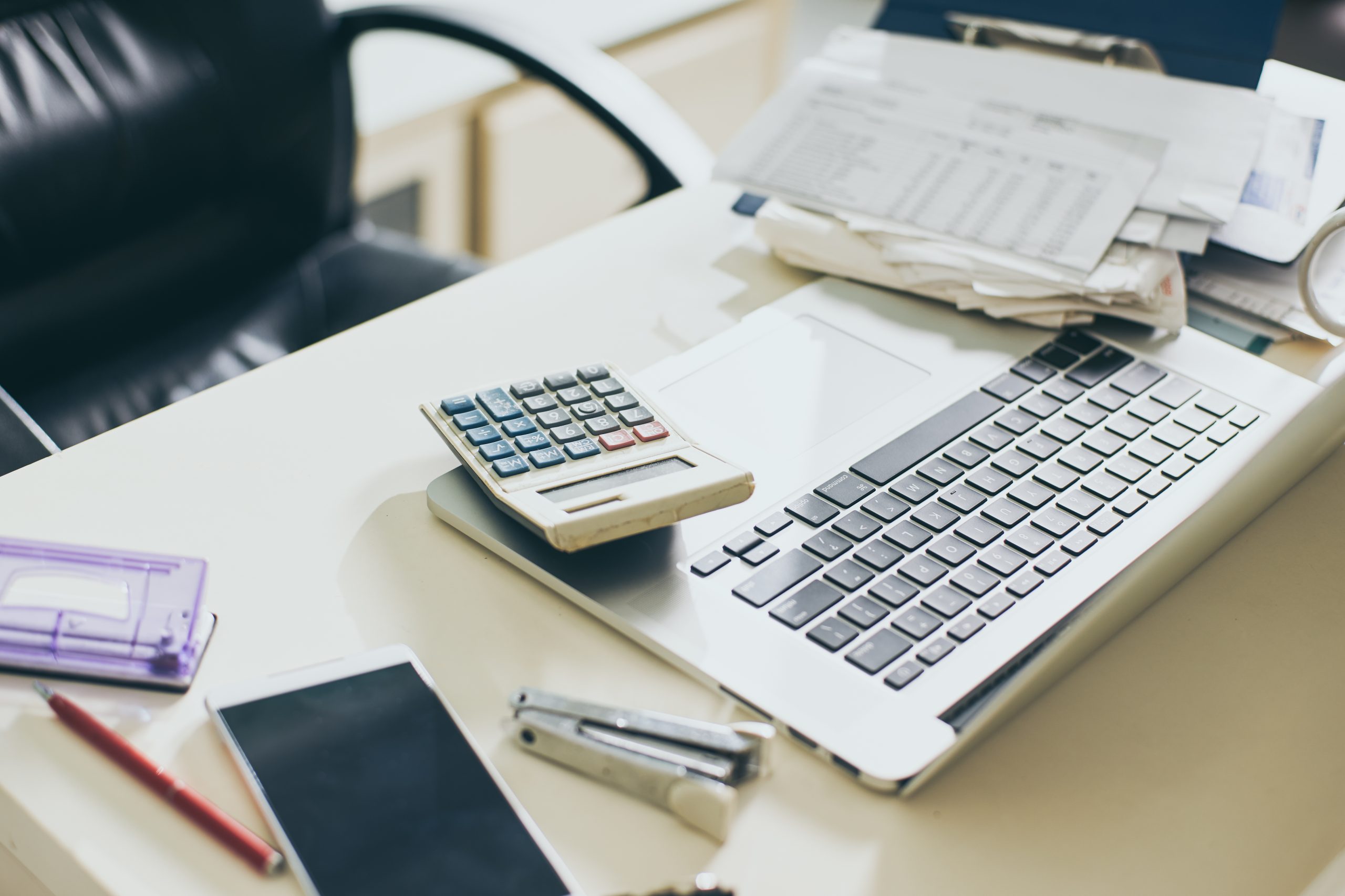 Calculator, documents and laptop on the table of business person Calculator and laptop sitting on desk among documents